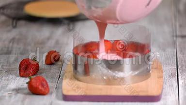 厨房里的女人做草莓慕斯蛋糕。 在糖果圈里浇草莓慕斯。 甜食